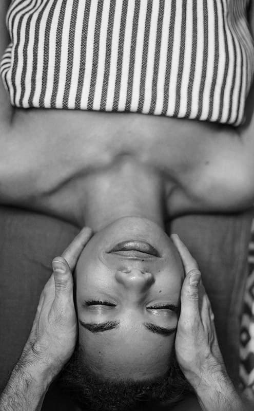 Des mains massants un visage féminin.