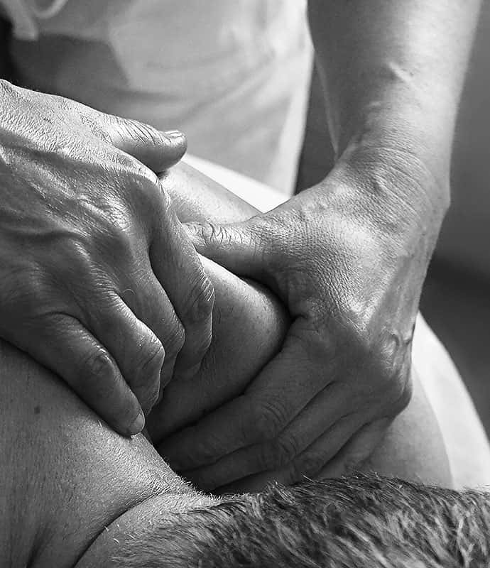 Des mains massant le haut du dos d'un homme.