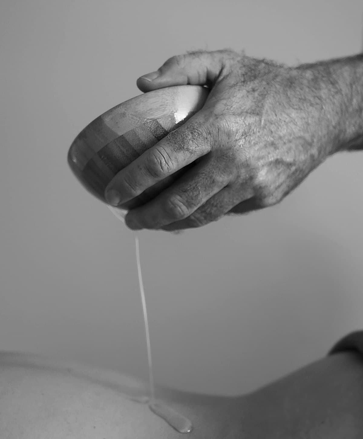 Main tenant un bol d'huile lors d'une séance de massage Abhyanga.